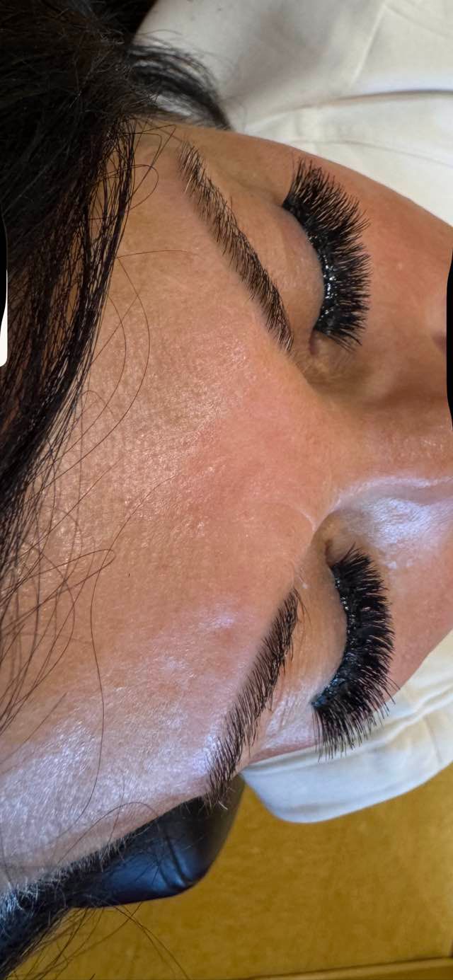 Close-up of a person's eye with thick, dark eyelashes and expertly shaped eyebrows.