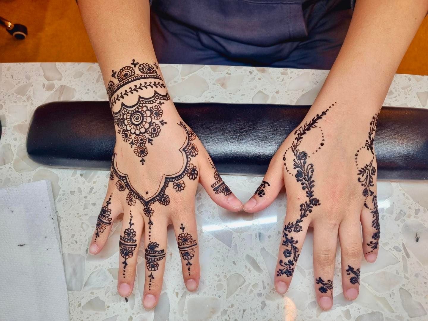 Hands adorned with intricate black henna designs.