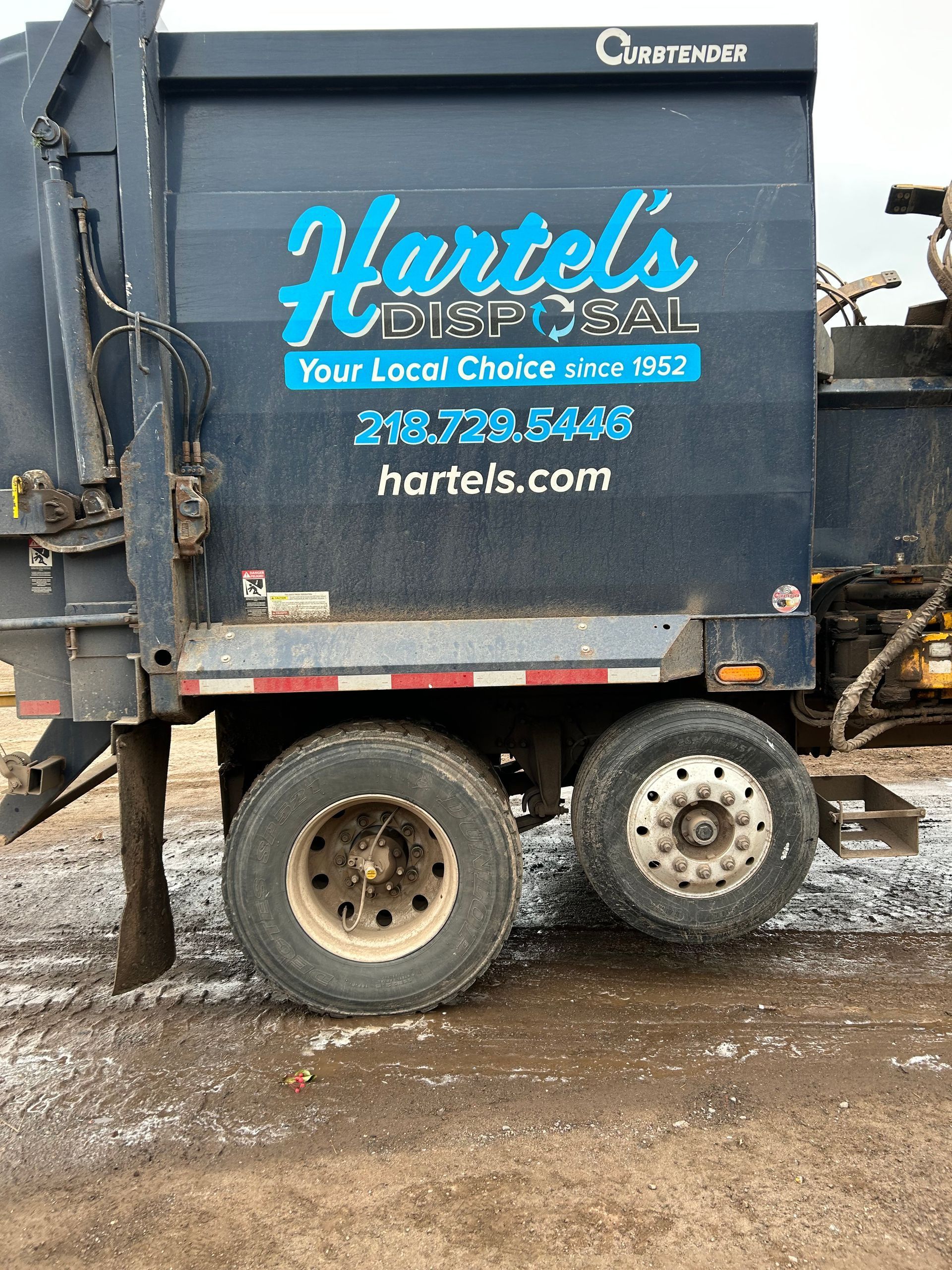 A garbage truck is parked on the side of the road