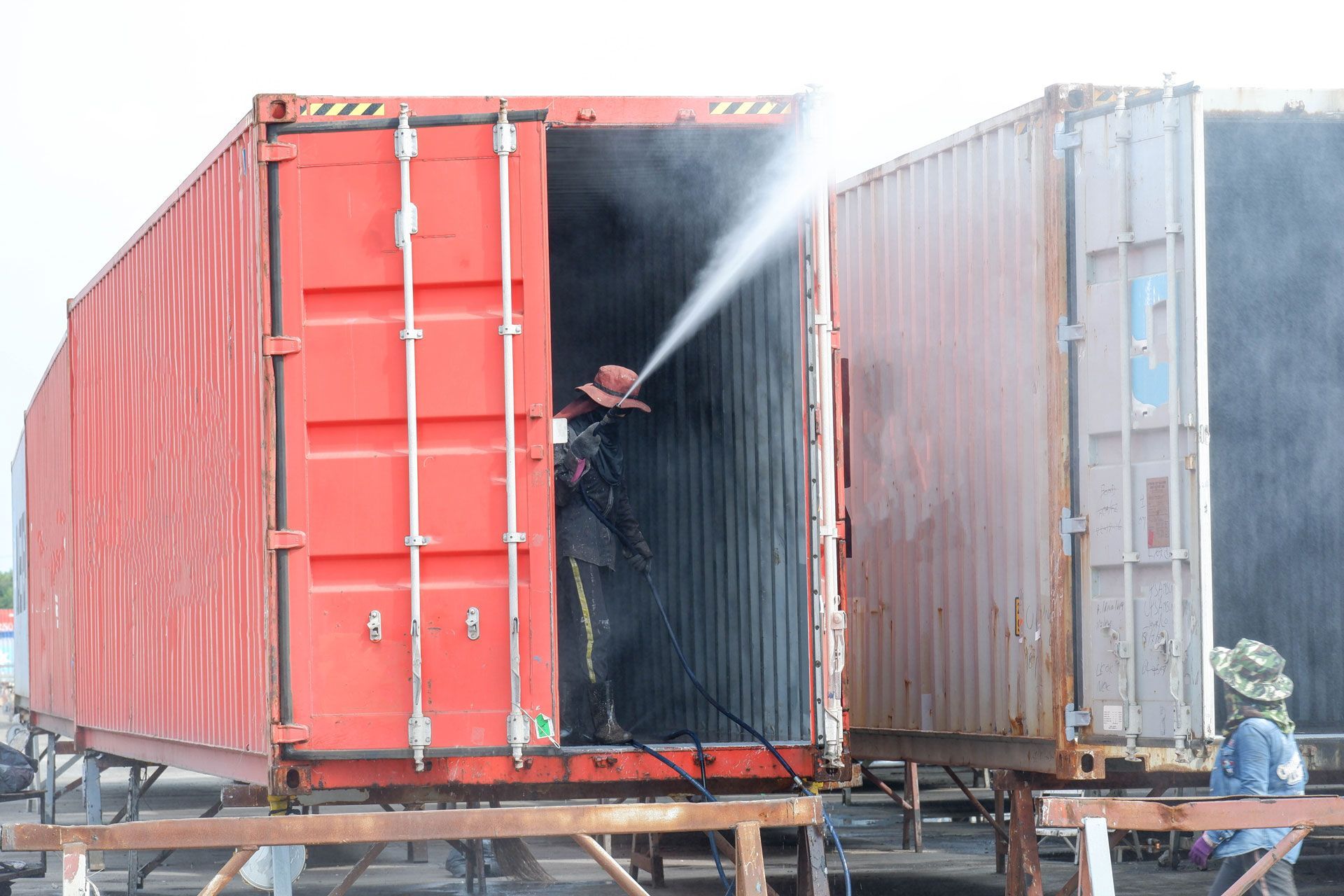 A man is spraying water into a shipping container