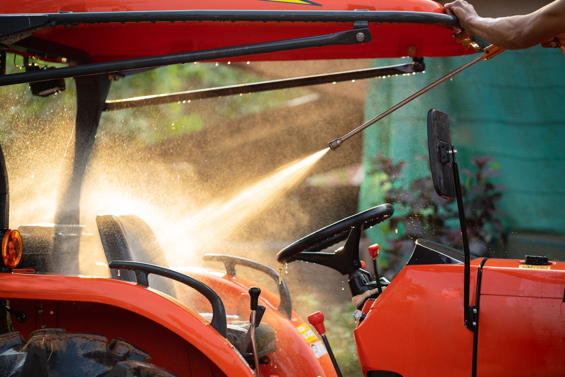 A person is washing a tractor with a high pressure washer