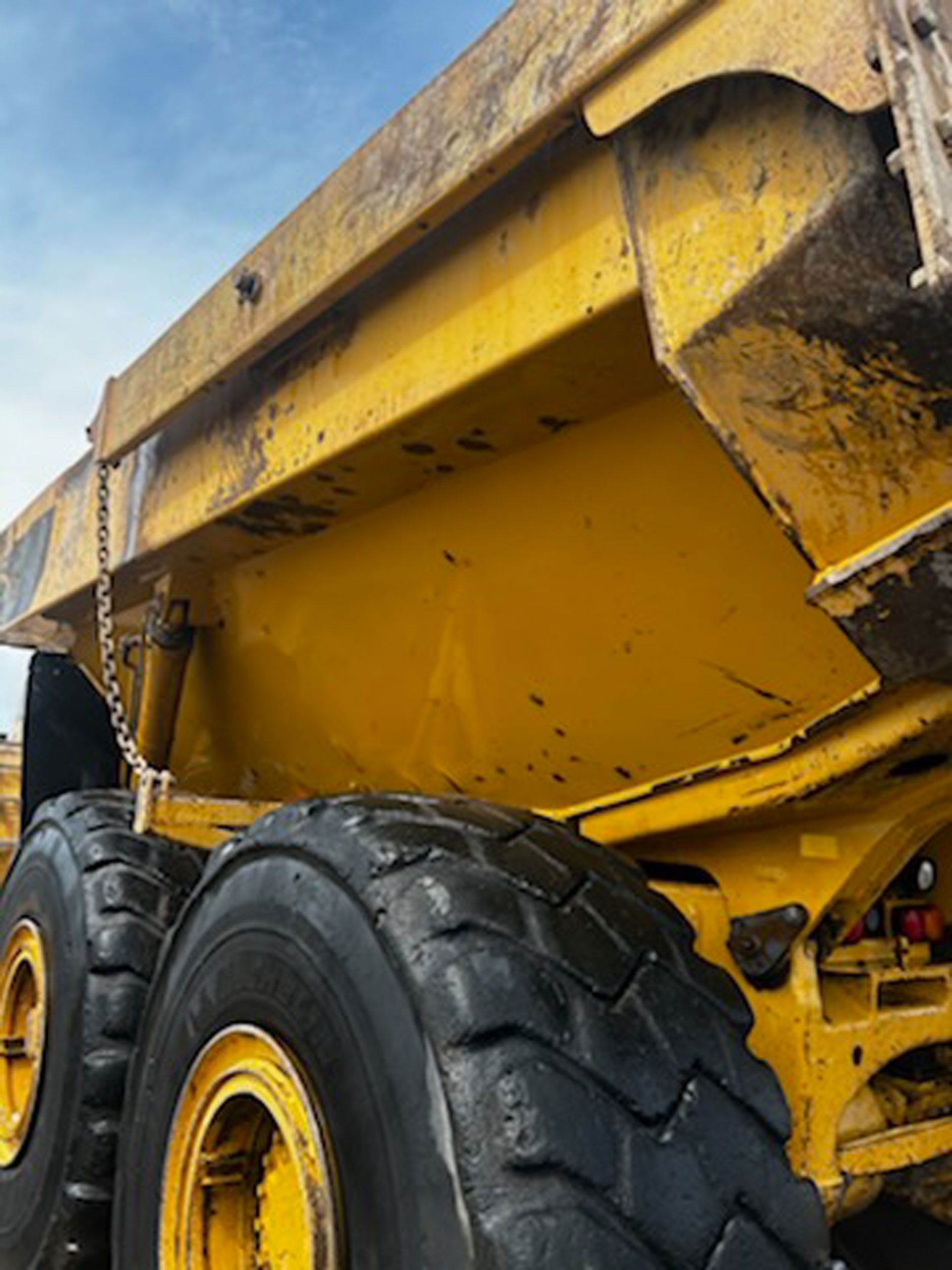 A yellow dump truck with black tires is parked on the side of the road