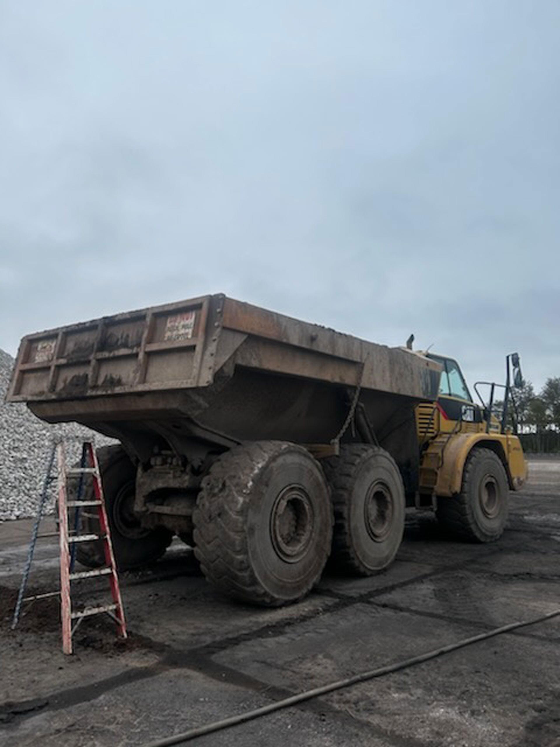 A dump truck is parked next to a ladder