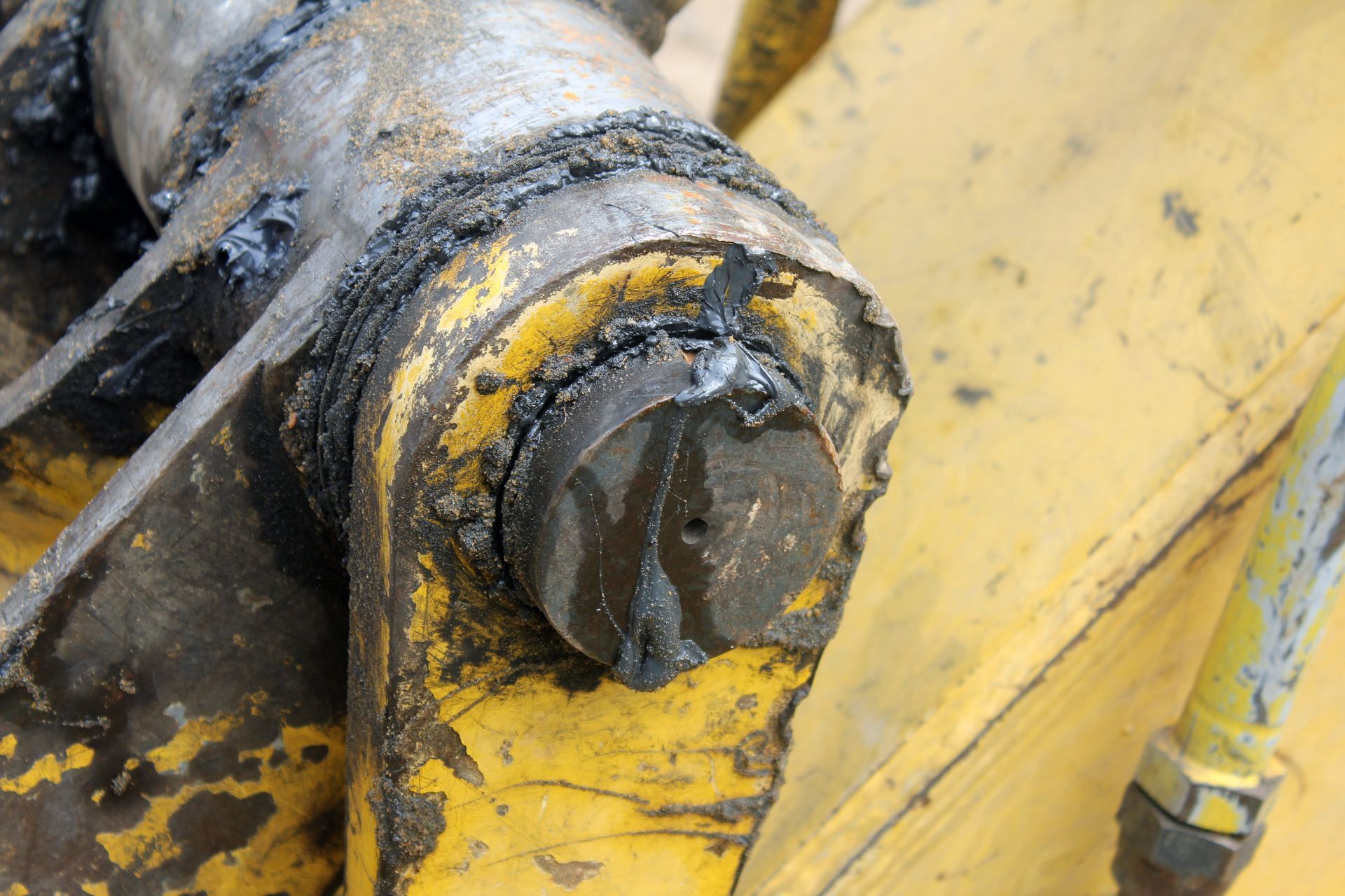 Yellow and dirty machine part with a circular black pin.