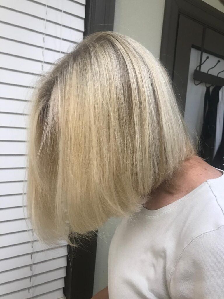 Blonde hair, crimped texture, shoulder-length bob, next to a window with blinds.