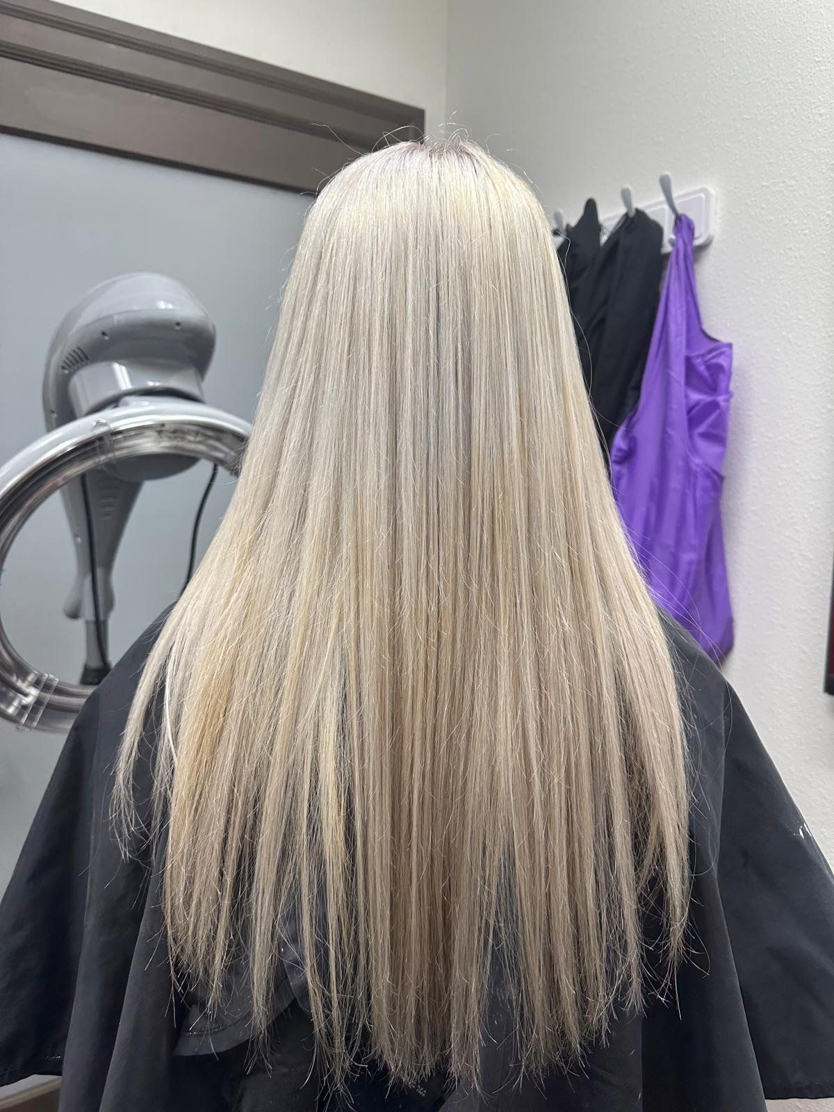 Woman's long, straight, blonde hair. In a salon, the hair is styled with a slight V-cut.