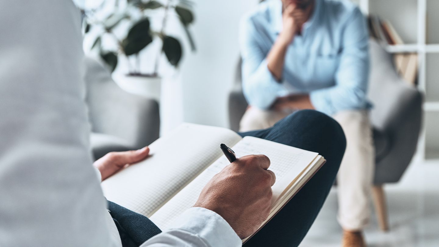 A man and a woman are sitting on a couch talking to each other.