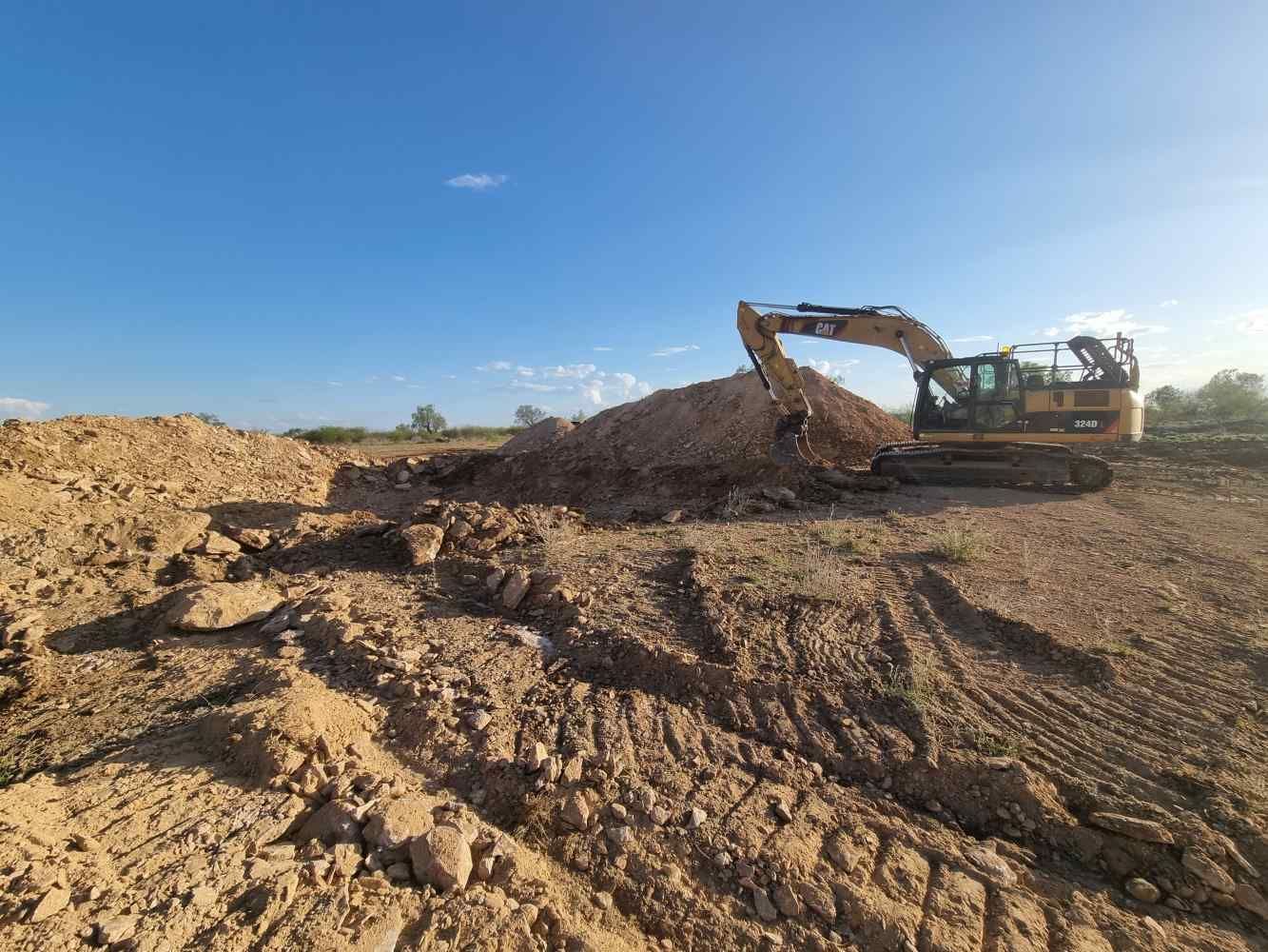 A Large Excavator is Moving Dirt in a Field — Burnett Contracting in Cloncurry, QLD