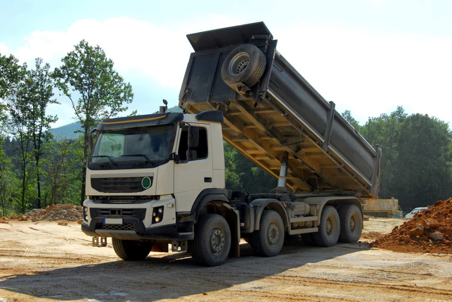 A Dump Truck is Parked in a Dirt Field With Its Bed Up — Burnett Contracting in Cloncurry, QLD