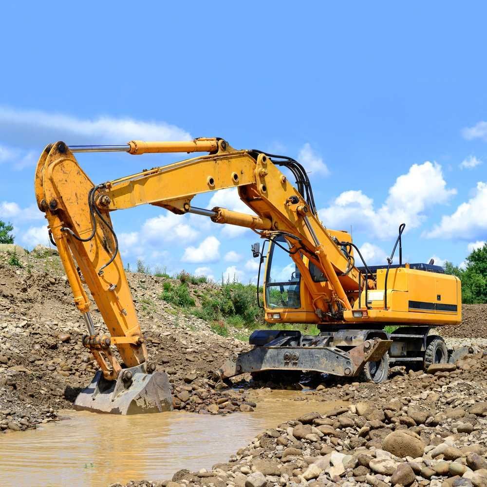 A Yellow Excavator is Digging a Hole in the Ground — Burnett Contracting in Cloncurry, QLD