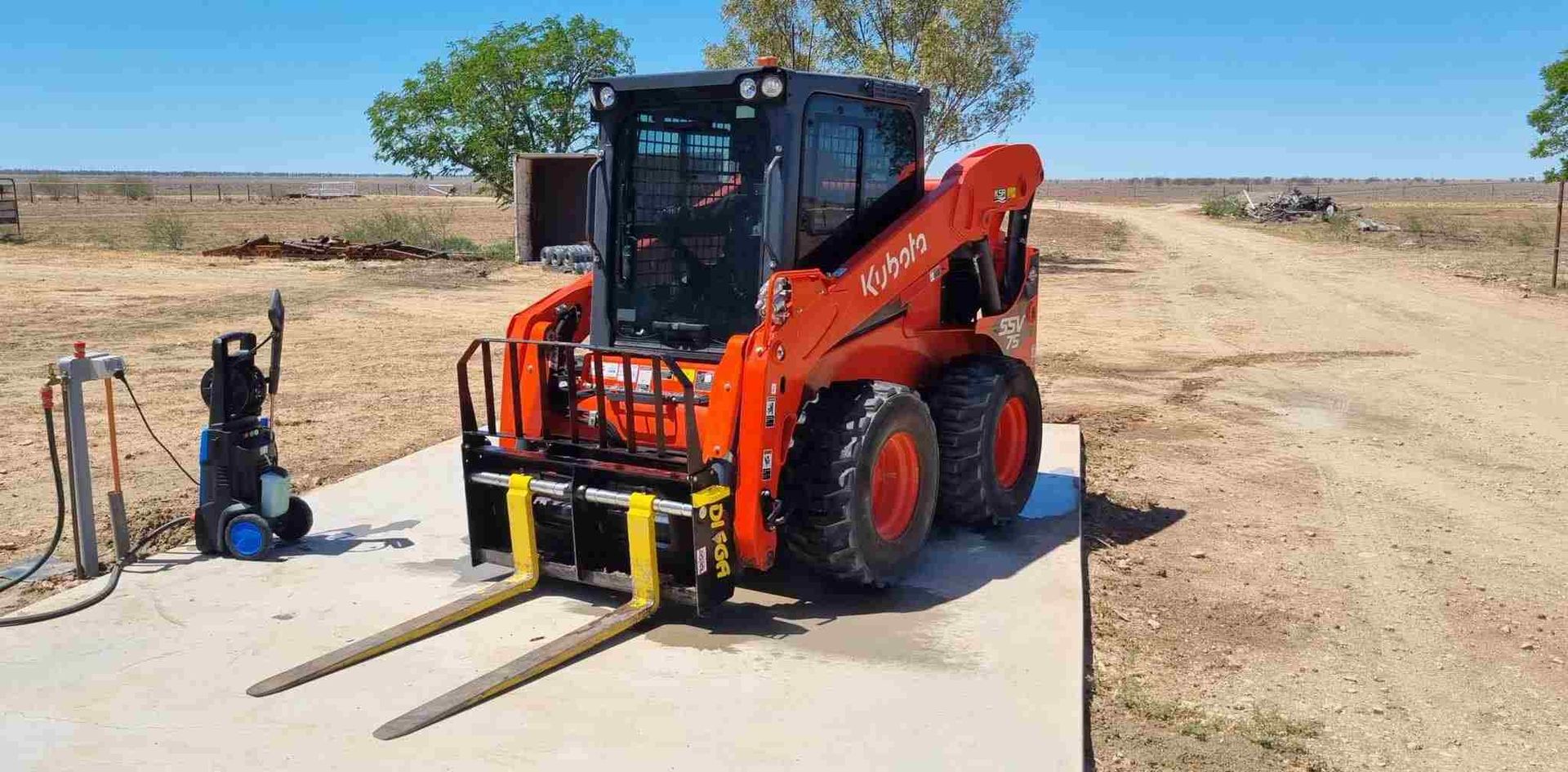 Orange Kubota Forklift Being Washed Outdoors on a Concrete Pad — Burnett Contracting in Burketown, QLD