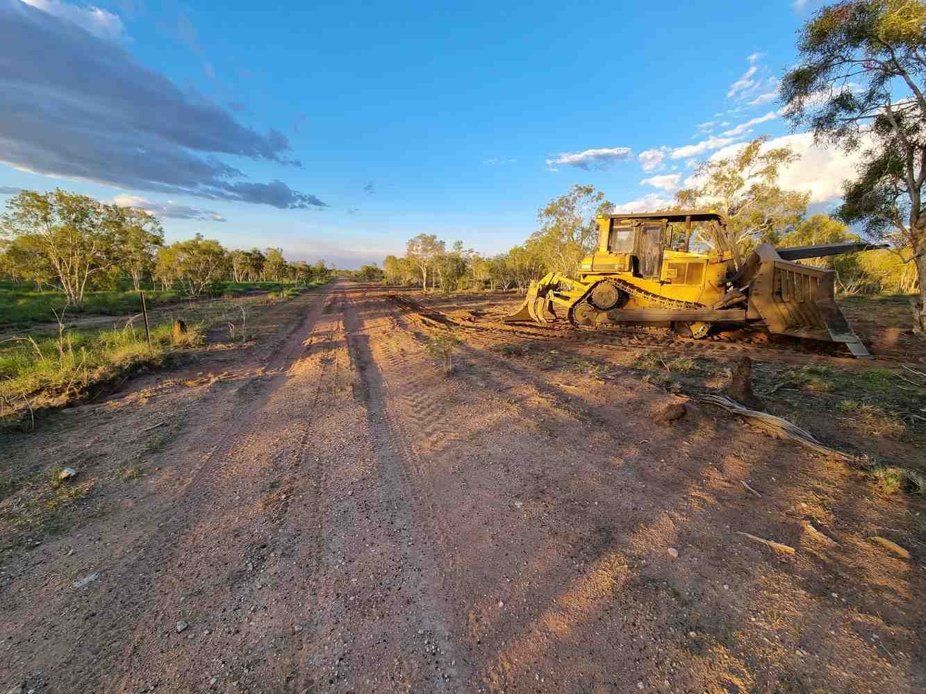 A Bulldozer is Sitting on the Side of a Dirt Road — Burnett Contracting in Cloncurry, QLD