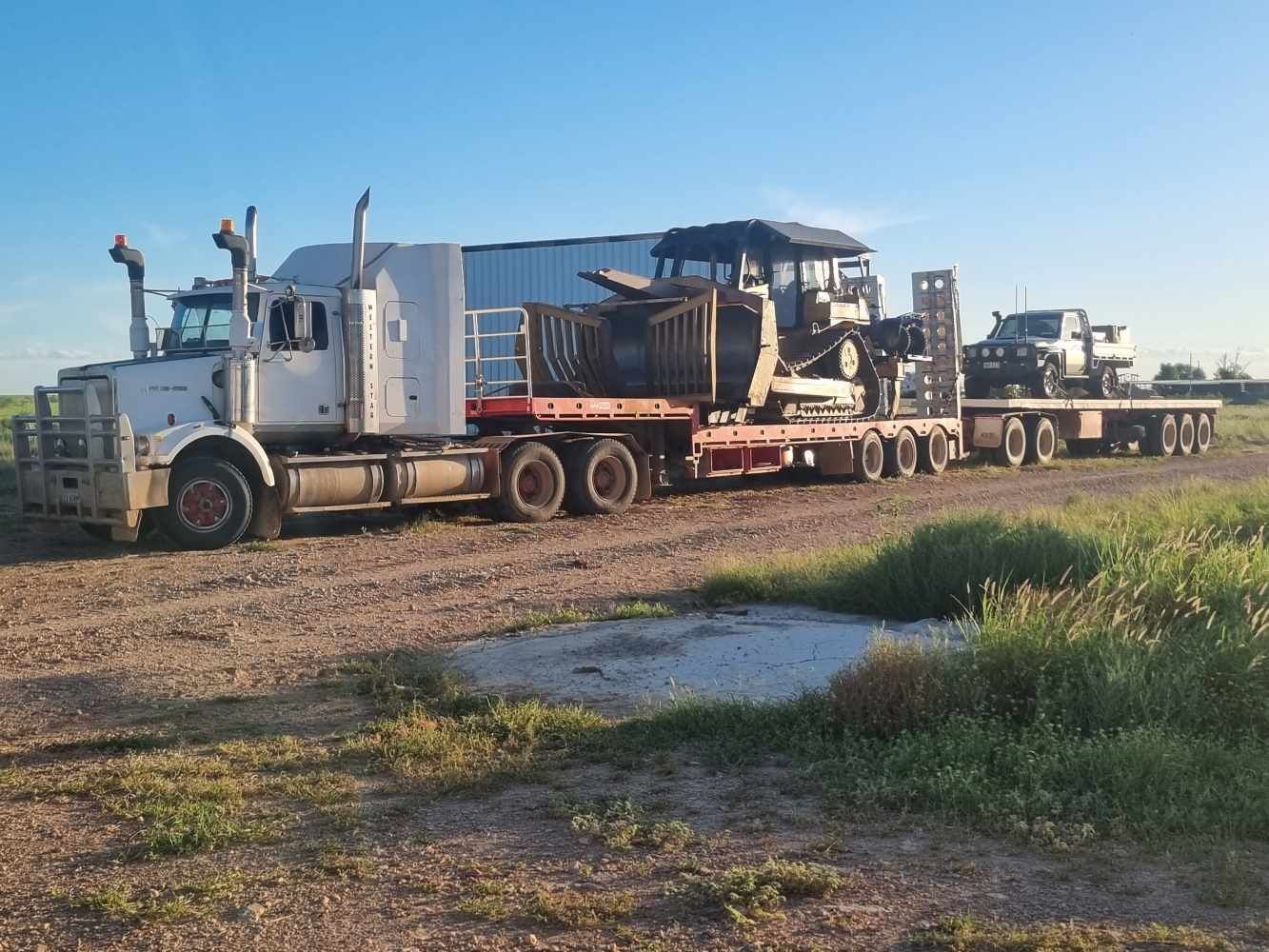 A Semi Truck is Carrying a Tractor on a Flatbed Trailer — Burnett Contracting in Cloncurry, QLD
