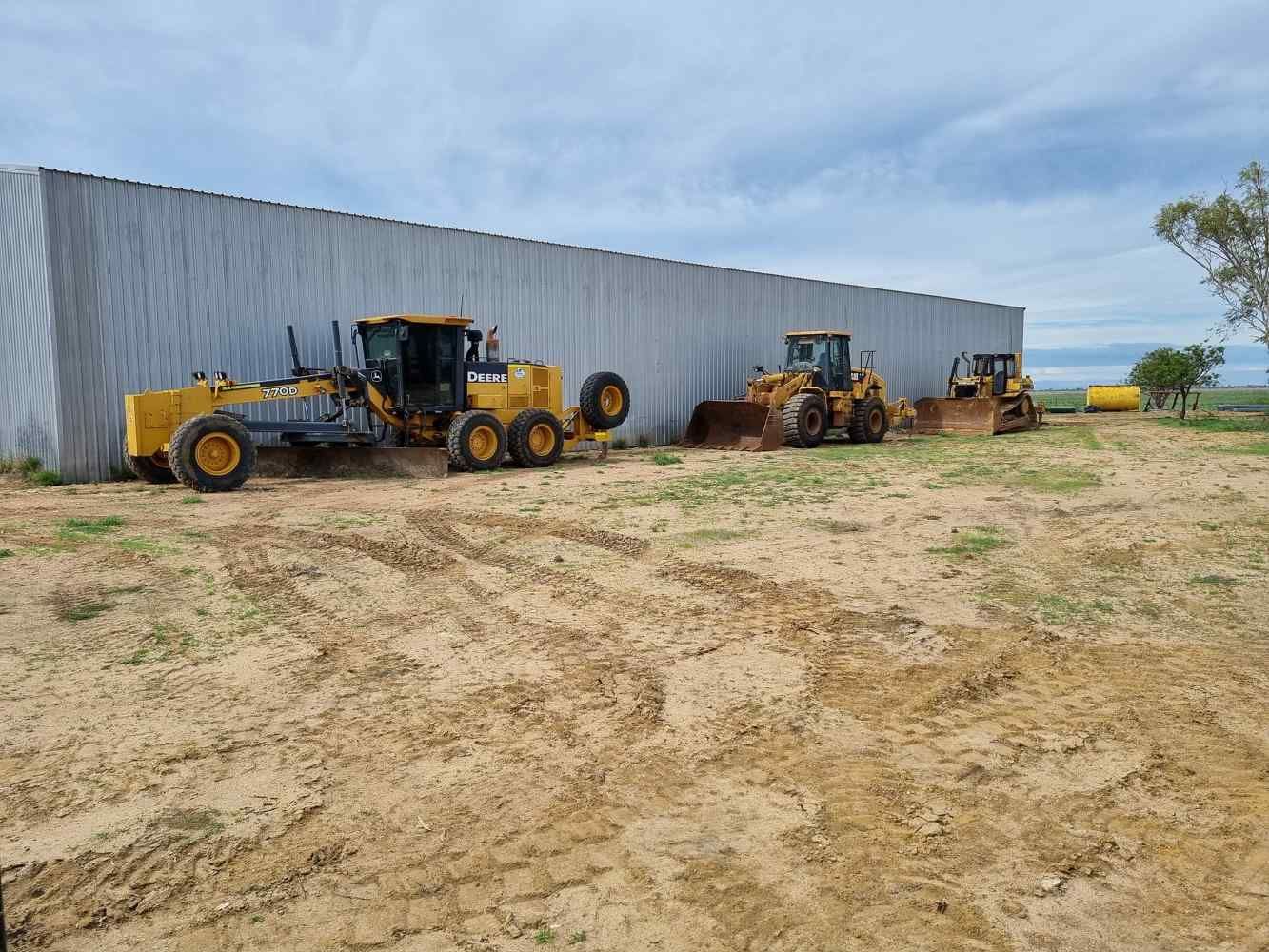 Three Tractors Are Parked in Front of a Building in a Dirt Field — Burnett Contracting in Cloncurry, QLD