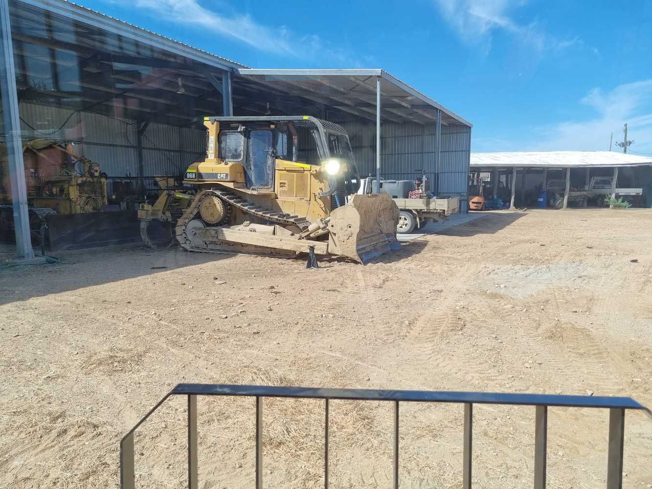 A Bulldozer is Driving Through a Dirt Field in Front of a Building — Burnett Contracting in Cloncurry, QLD