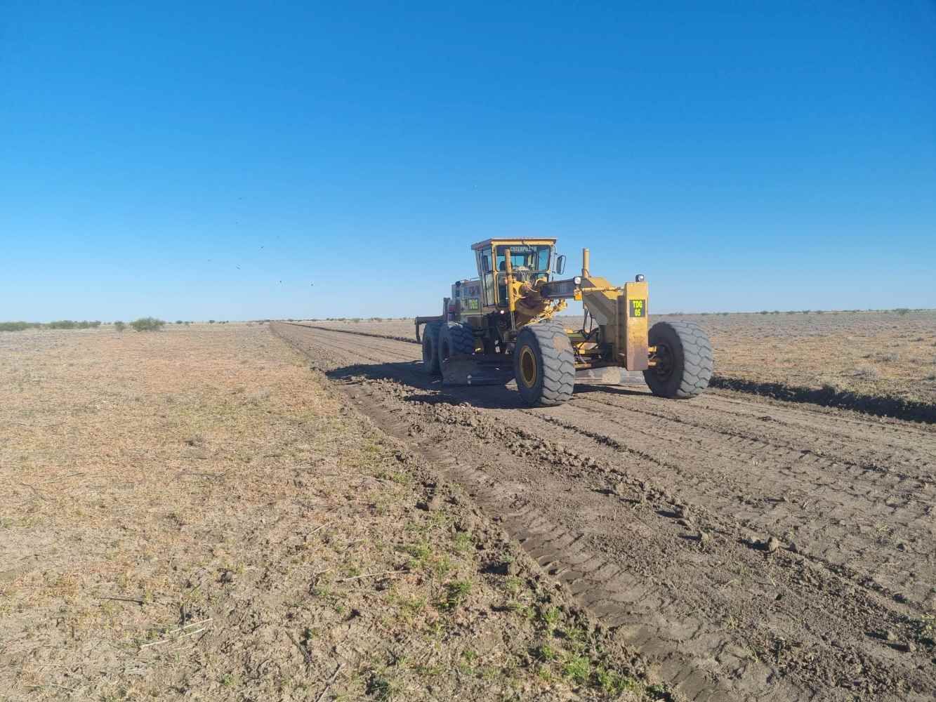 Yellow Tractor is Driving Down a Dirt Road in a Field — Burnett Contracting in Cloncurry, QLD