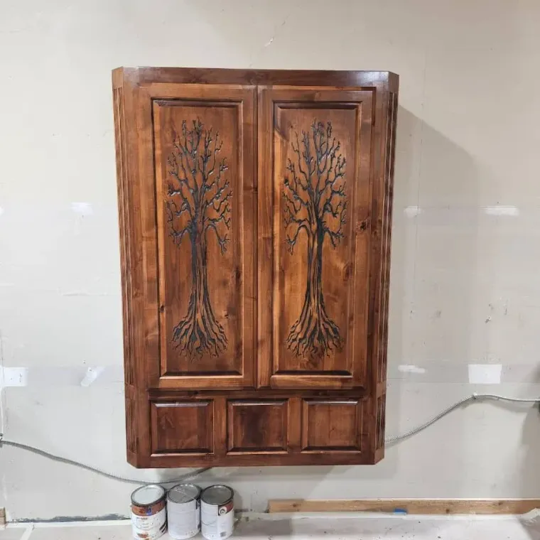 Wall-mounted wooden cabinet with open doors and a fold-down table, showing shelves and interior details. Brown finish.