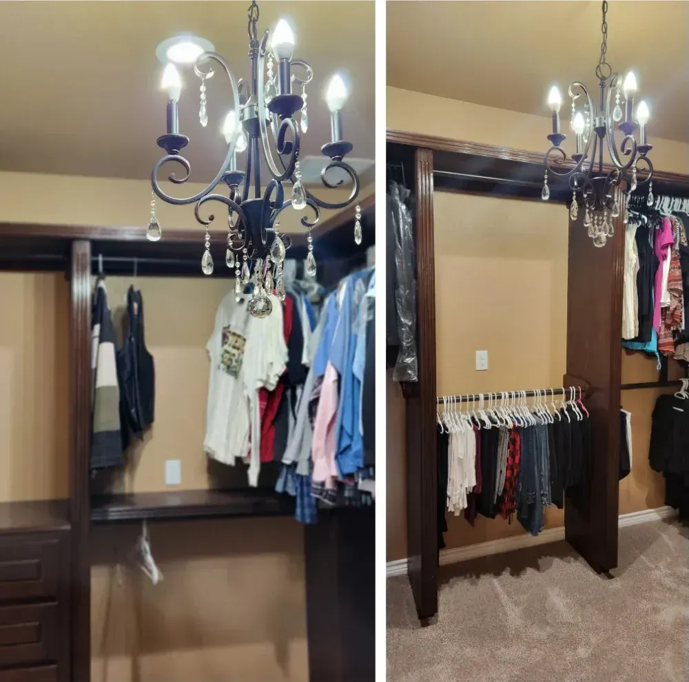 A walk-in closet with dark brown shelving, clothes, and a chandelier with crystals.