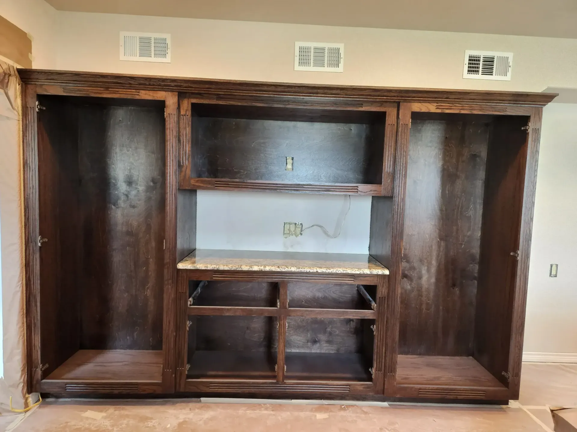 Brown wooden built-in entertainment center with open shelving and cabinet spaces; unfinished.