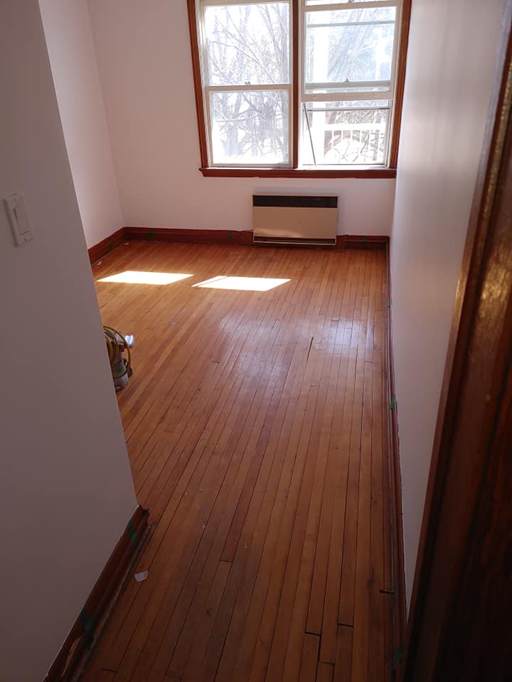 Une pièce vide avec du parquet et une fenêtre.