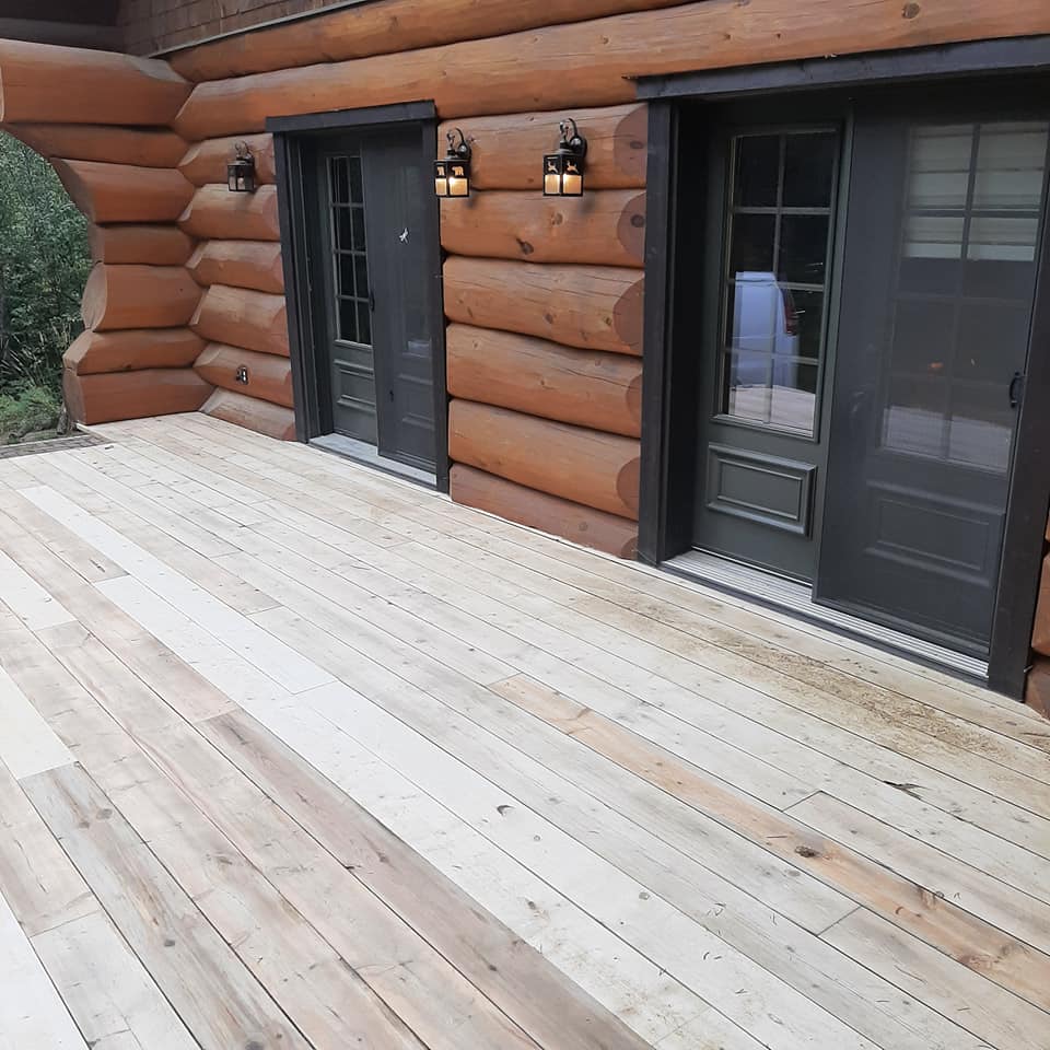 Une cabane en rondins avec une terrasse en bois devant elle