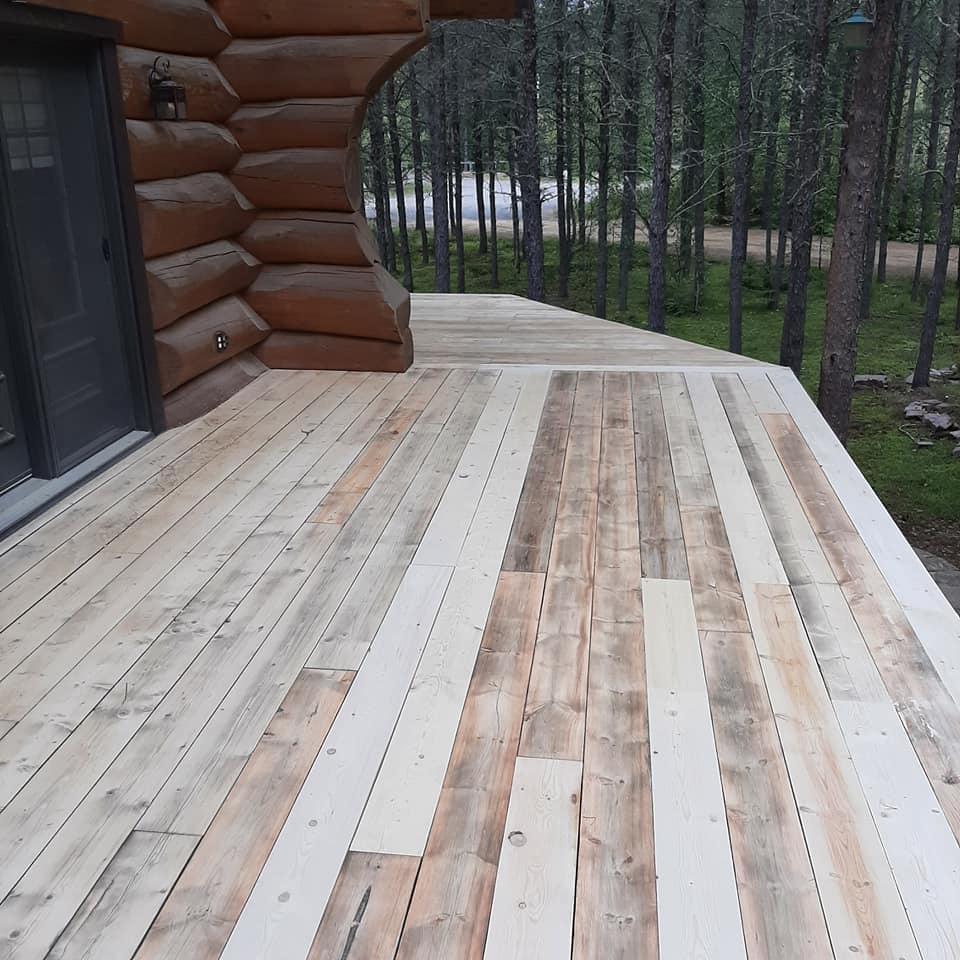 Une terrasse en bois avec une cabane en rondins en arrière-plan