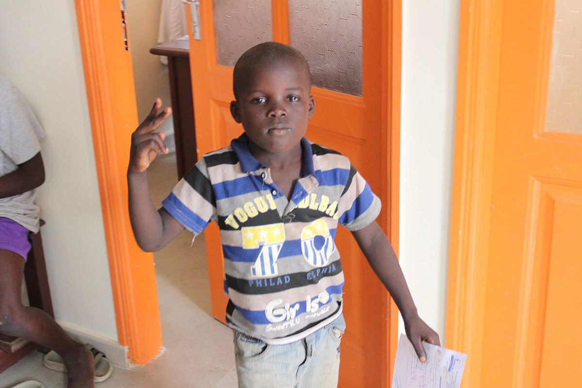 A young boy wearing a striped shirt with the word togo on it