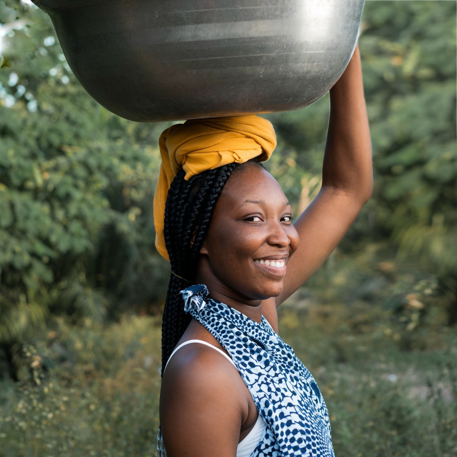 A woman is carrying a large bowl on her head.