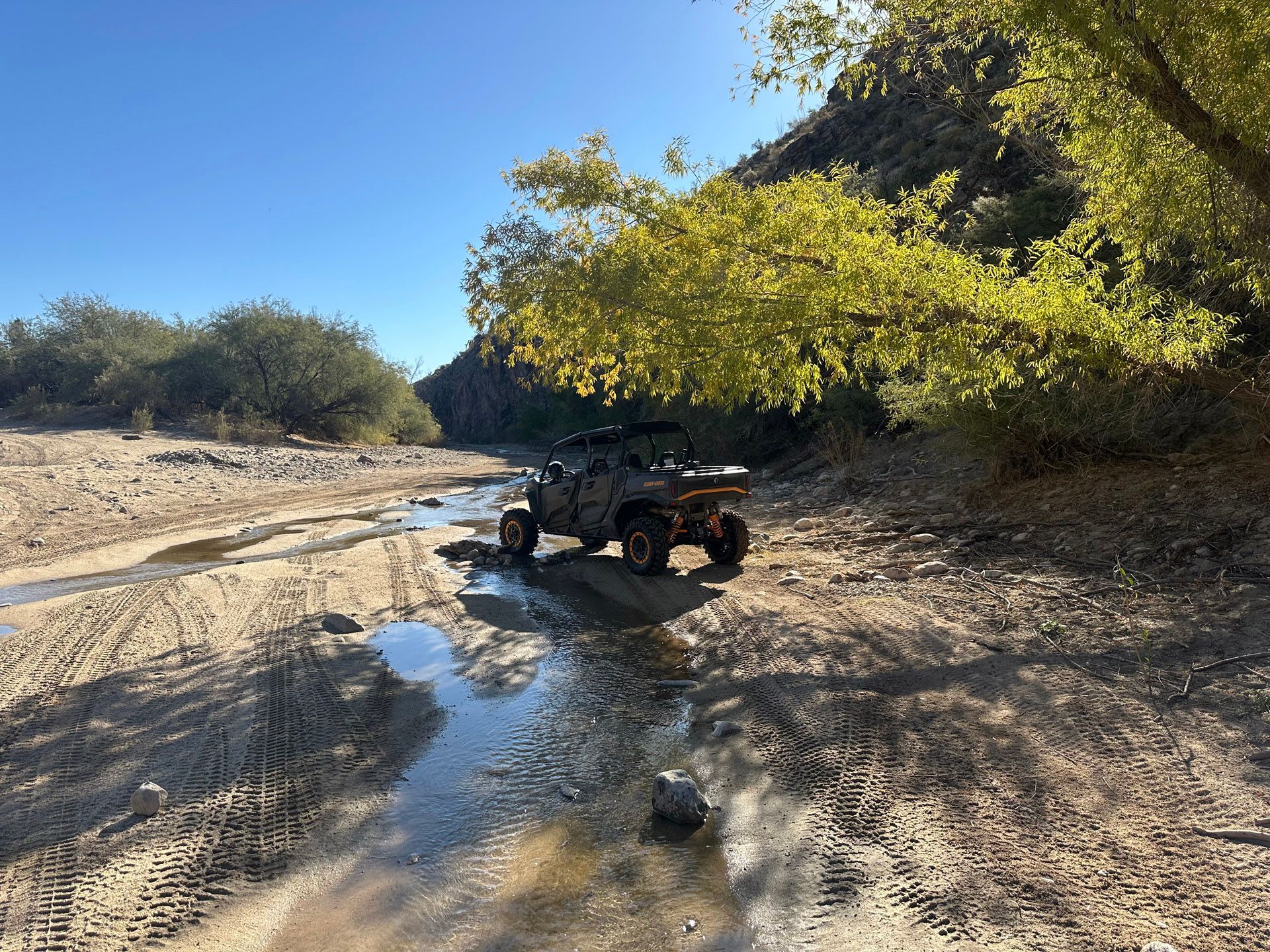A jeep is driving down a dirt road next to a river.