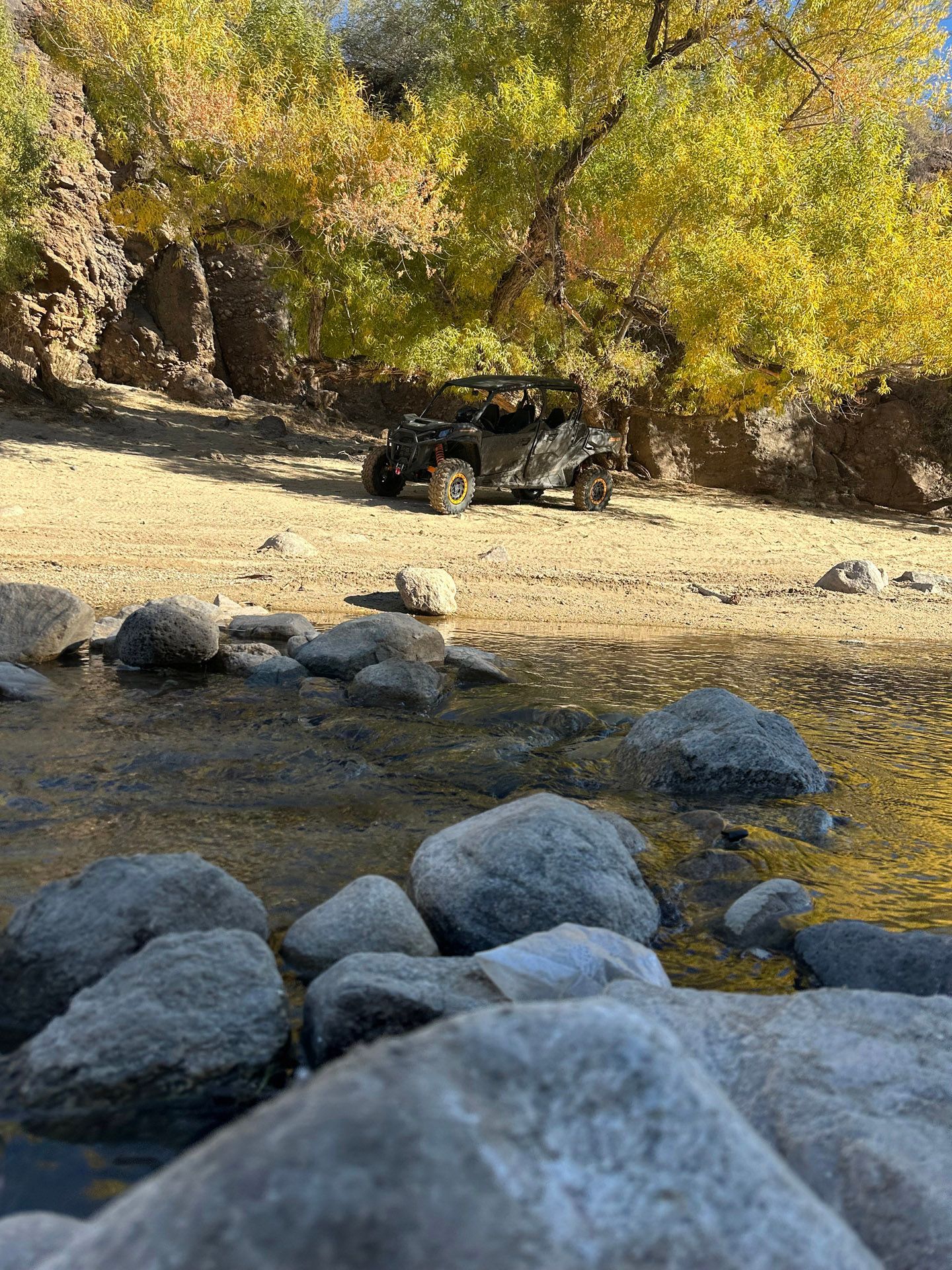A jeep is driving down a dirt road next to a river.
