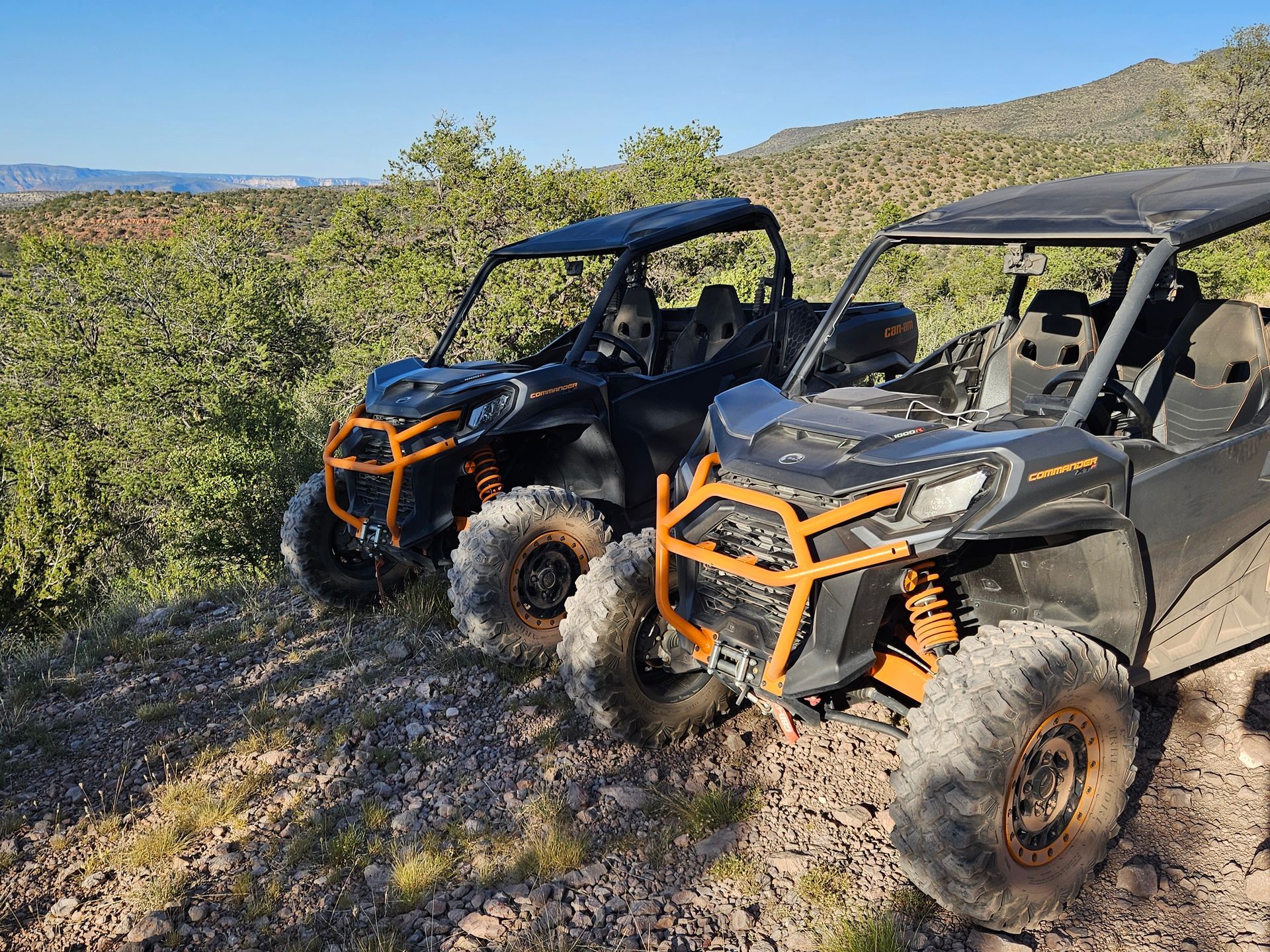 A black atv is driving down a dirt road next to a river.