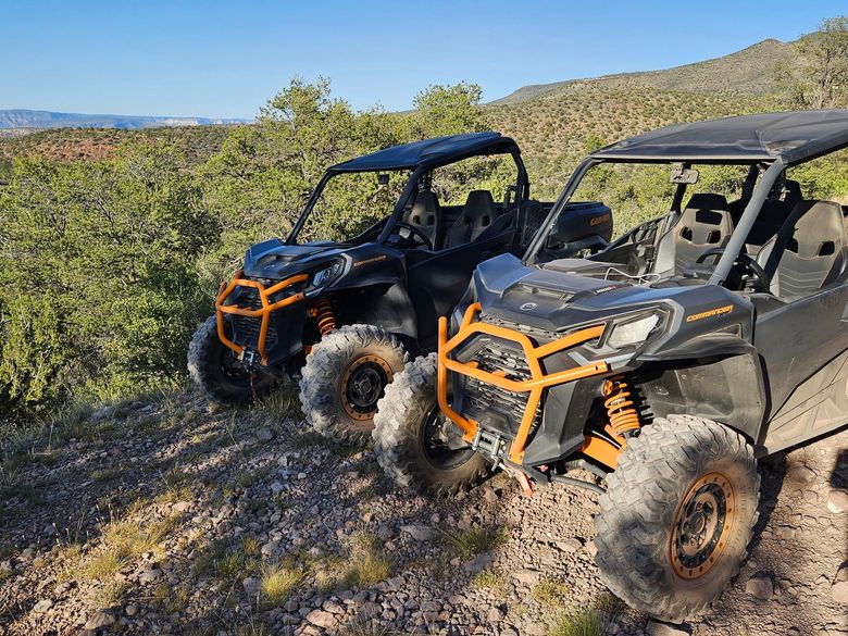 Two atvs are parked next to each other on a dirt road.