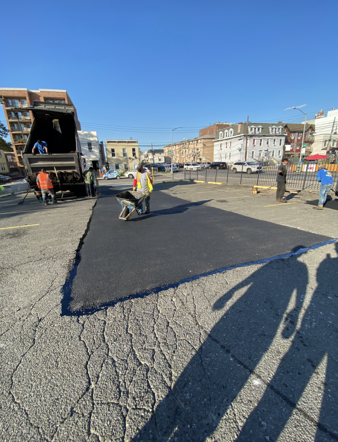 An orange and yellow triangle is sitting on the ground next to a pothole.