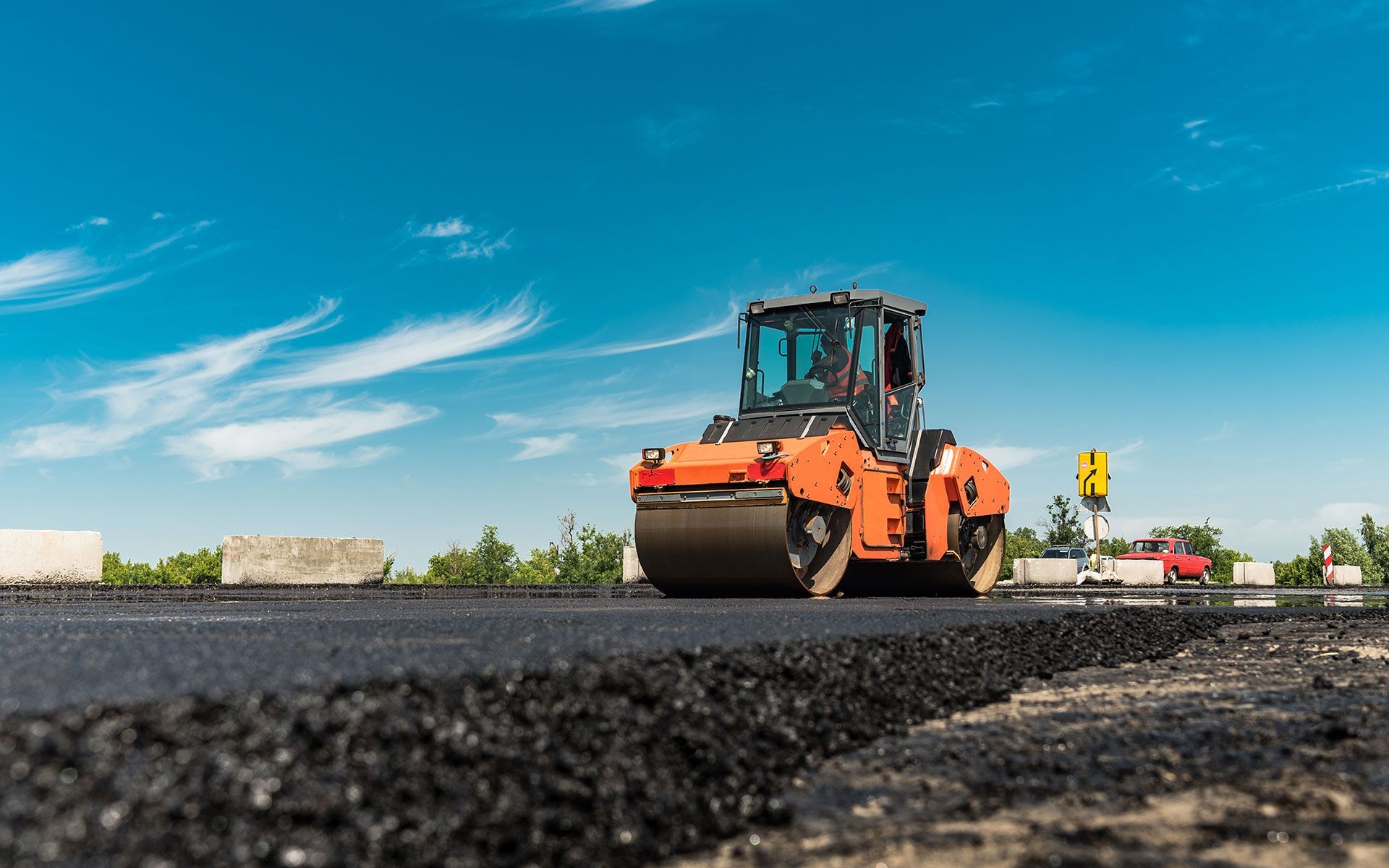 A roller is rolling asphalt on a road under construction.