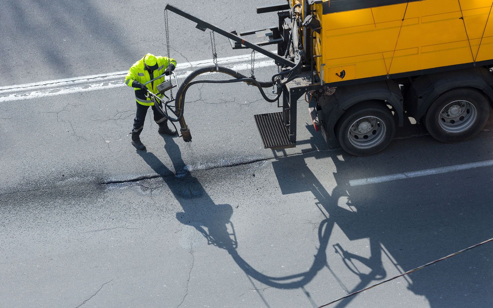 A man in a yellow vest is standing next to a yellow truck.