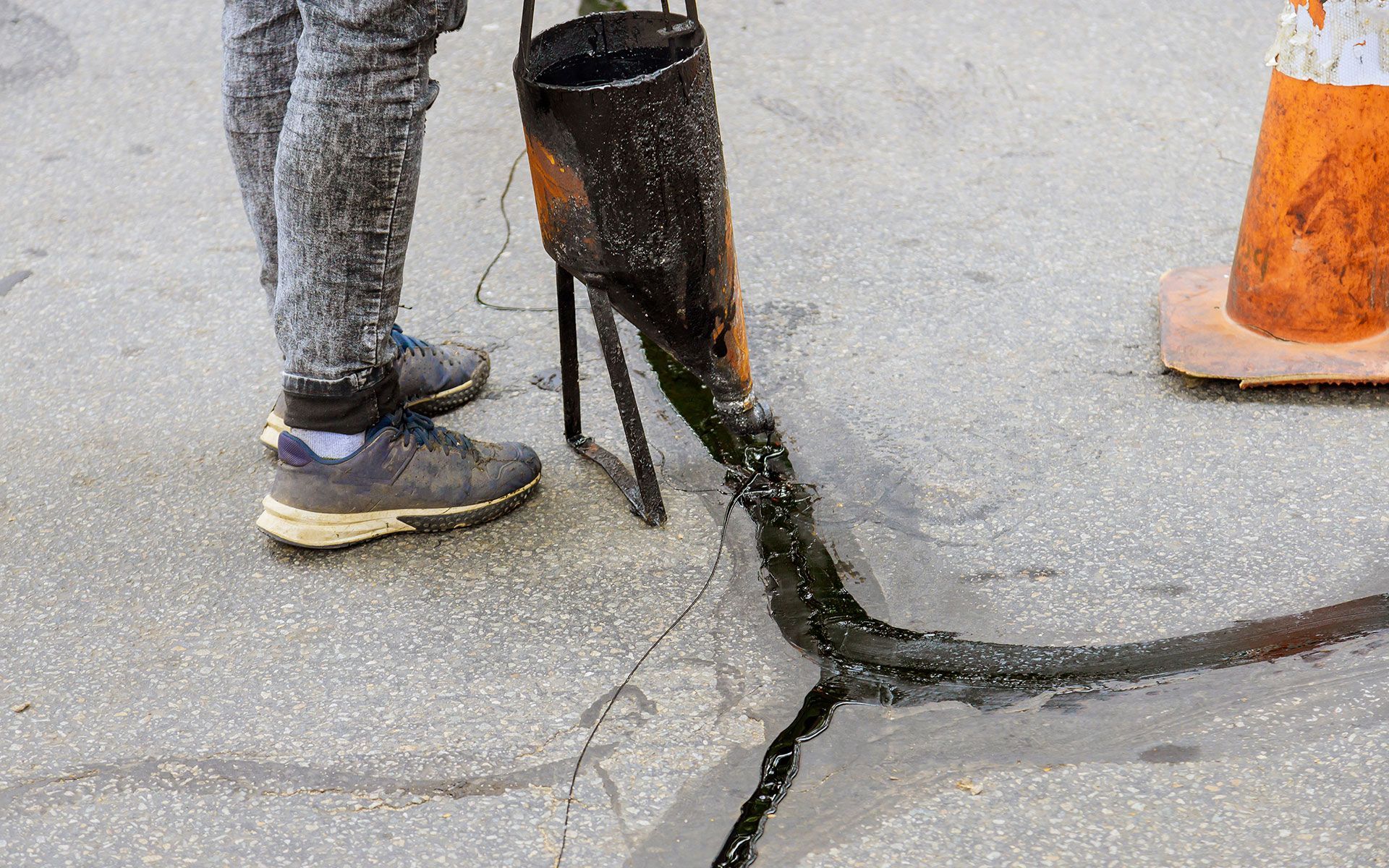 A person is standing next to a bucket of liquid on the ground.