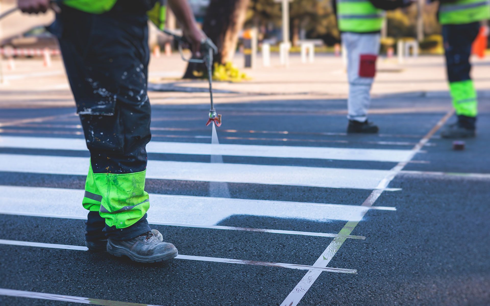 A man is painting a crosswalk on the road.