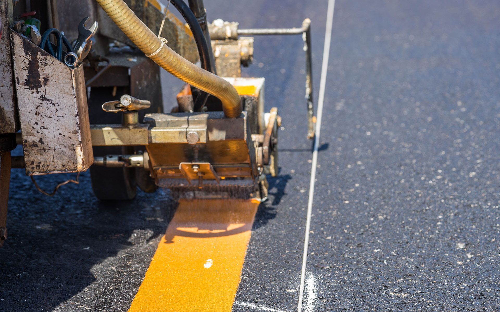 A machine is painting a yellow line on the road.