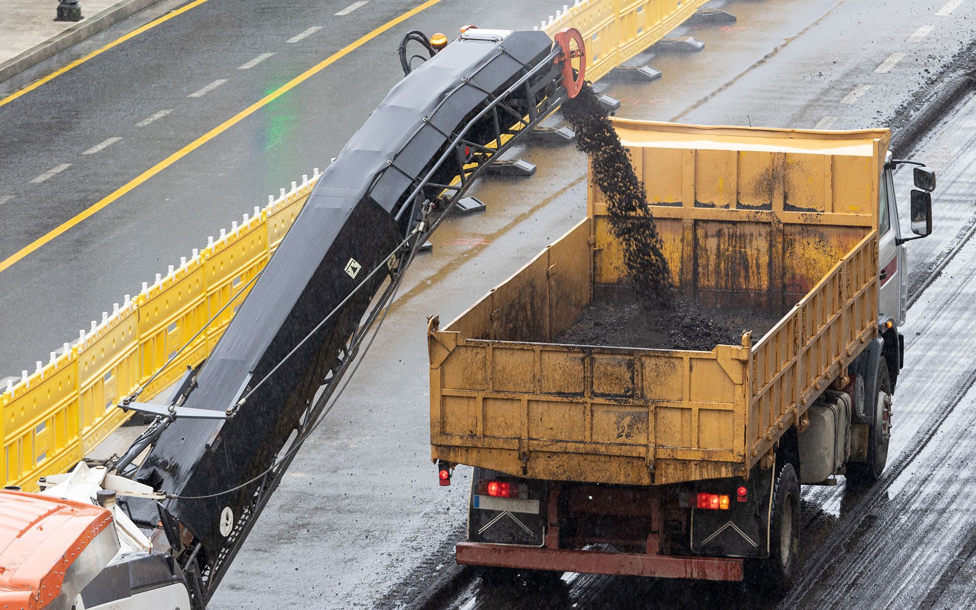 A dump truck is being loaded with coal on the side of the road.