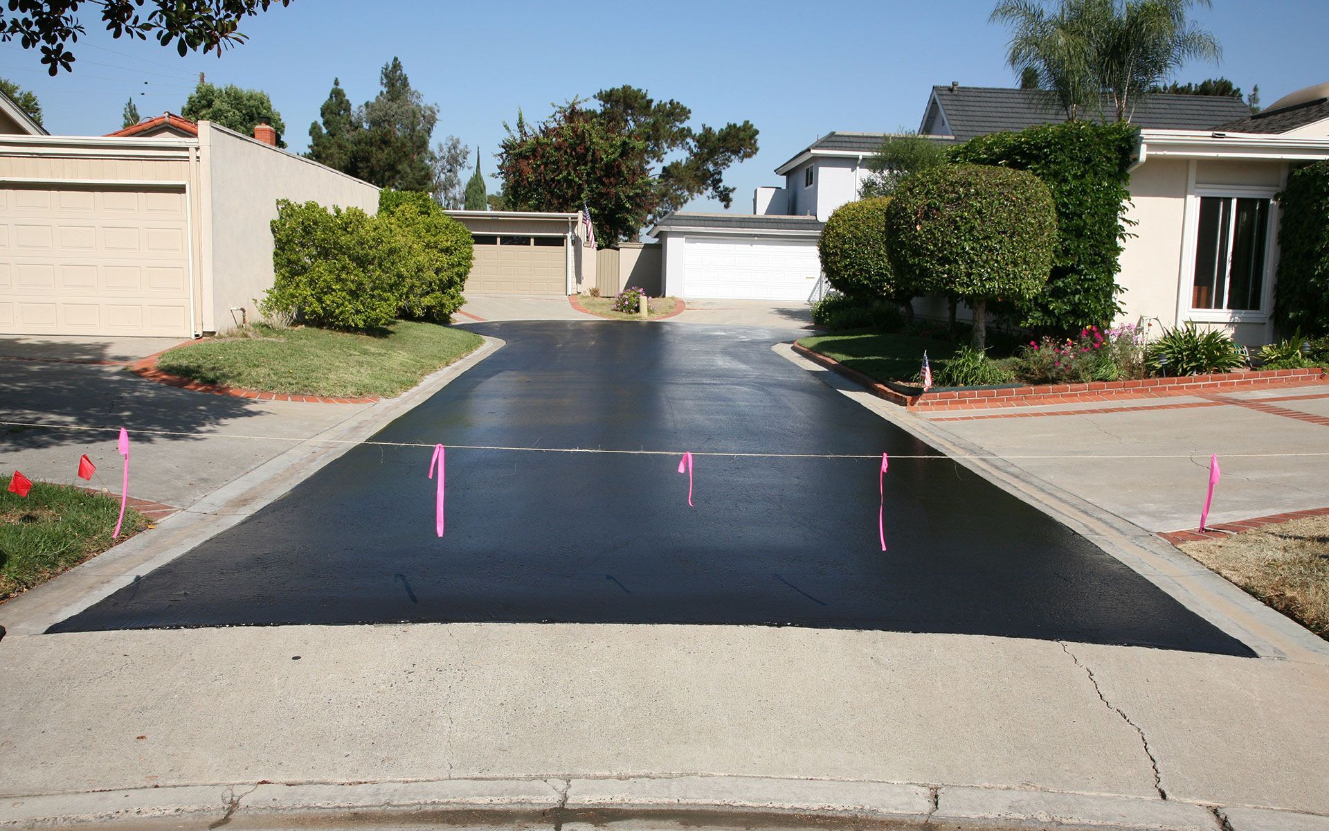 A residential driveway with a few pink markers on it