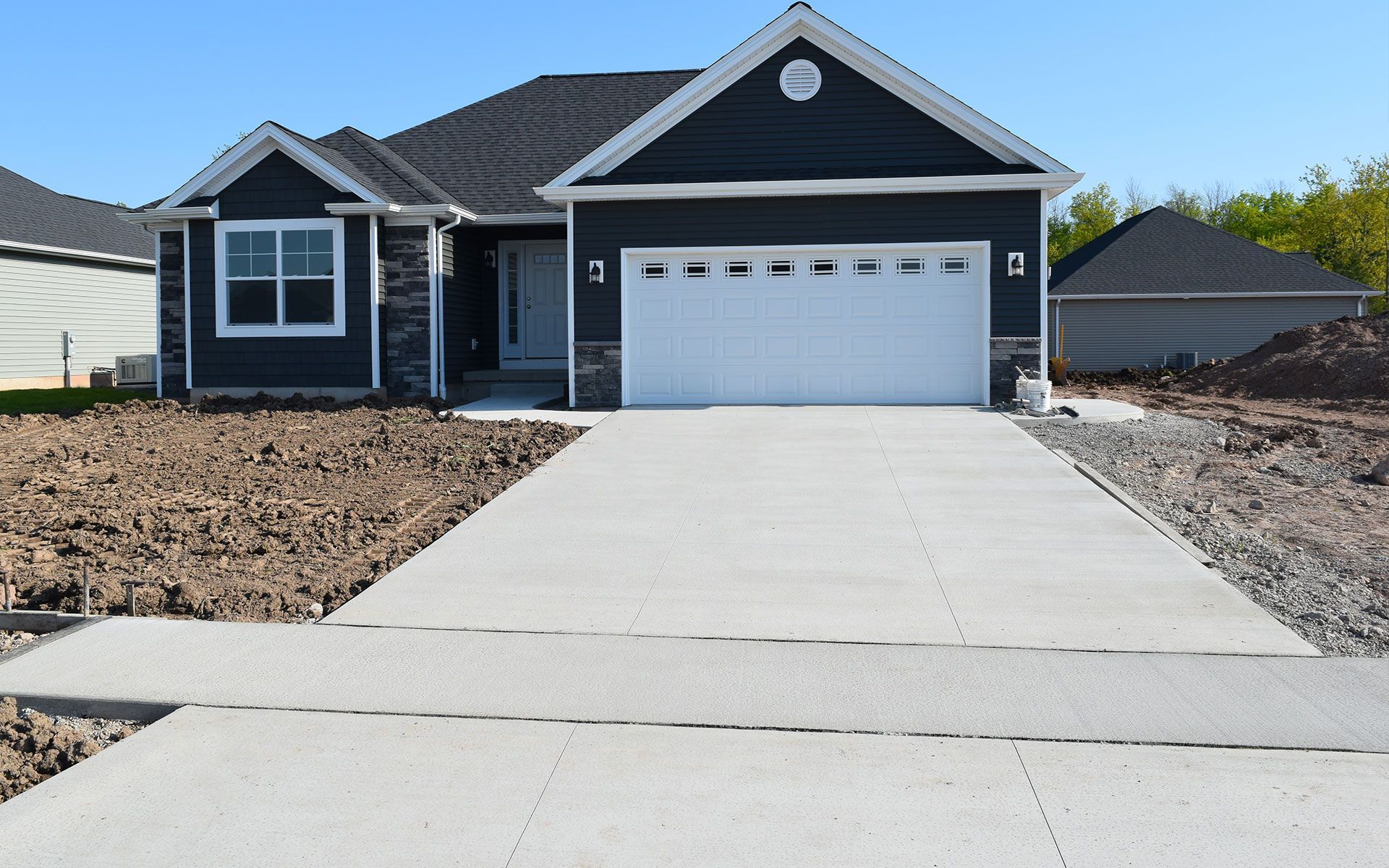A black house with a white garage door and a concrete driveway