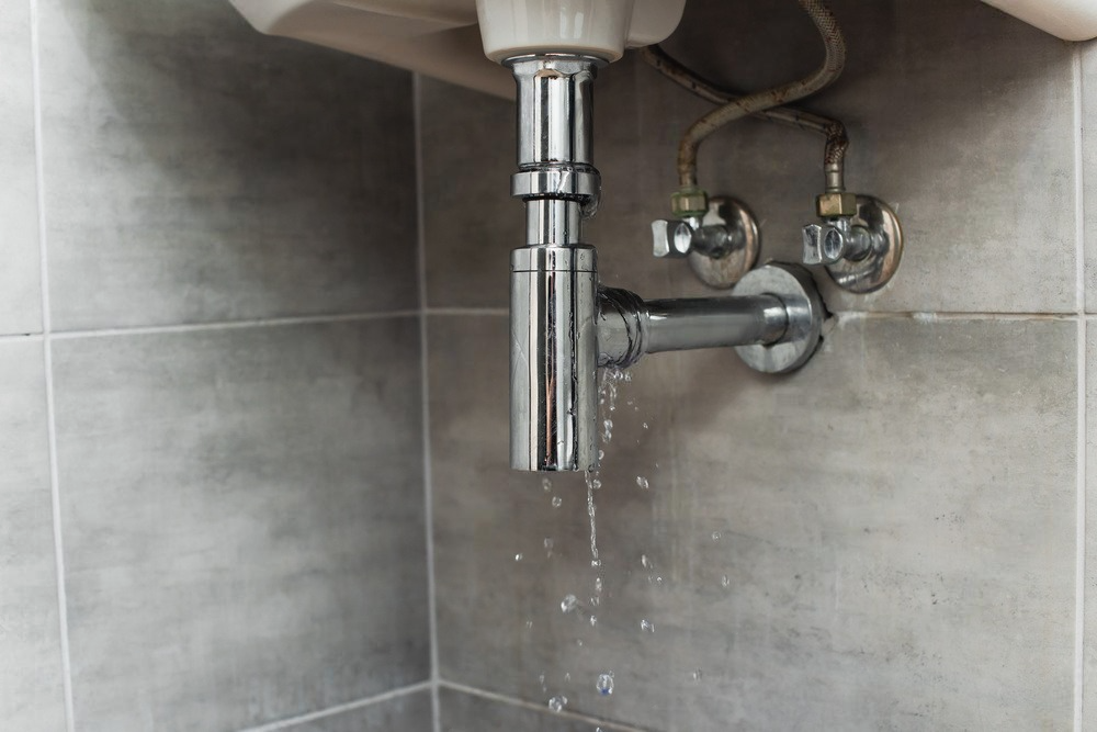 a bathroom sink with water leaking from the drain pipe .