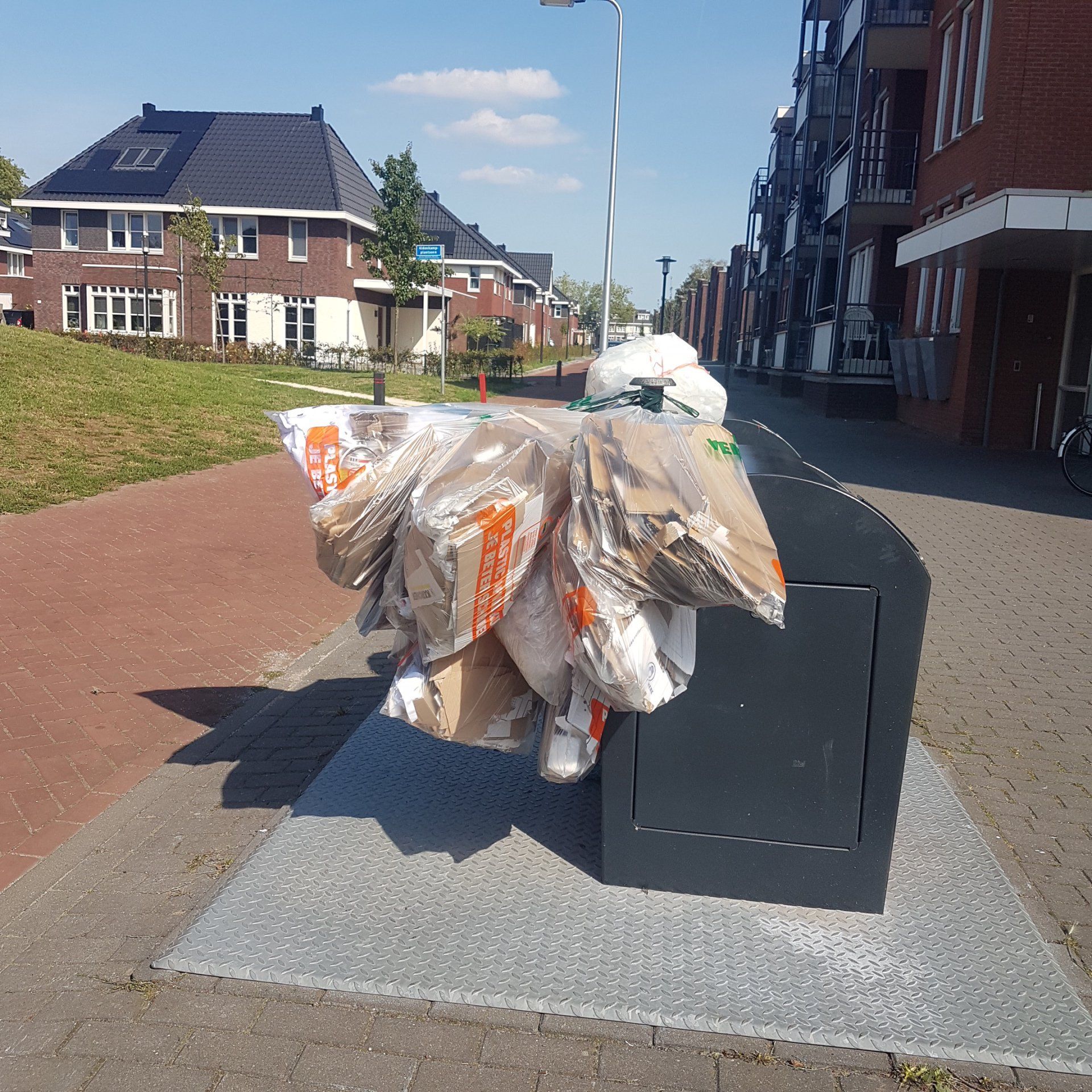 Een stapel afval ligt op de stoep voor een bakstenen gebouw