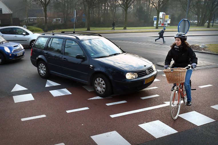 Een vrouw fietst voor een auto