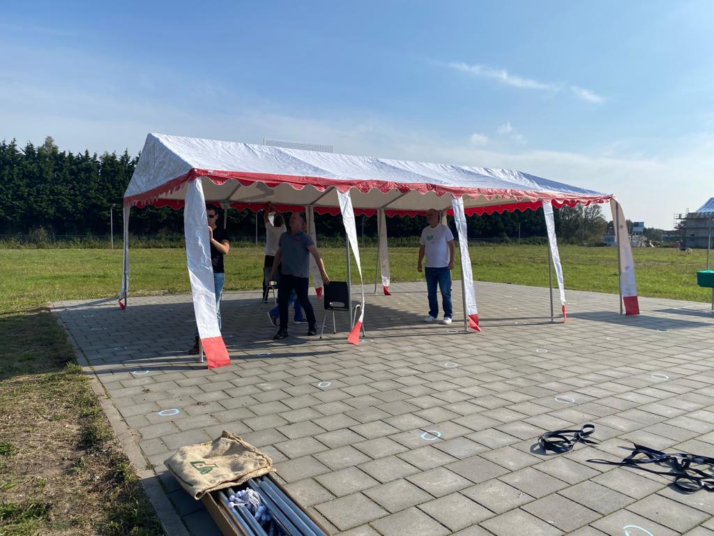 Een groep mensen staat onder een tent in een veld.