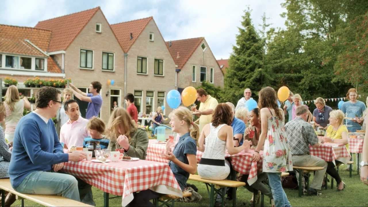 Een groep mensen zit aan tafels in een park.