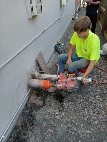 A man is using a machine to cut a hole in a wall.