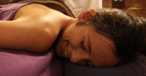 a woman is smiling while laying on a purple pillow