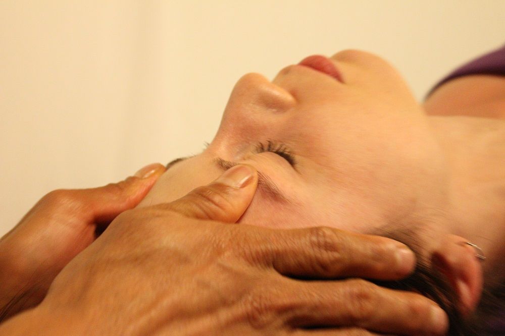 a woman is getting a head massage with her eyes closed .