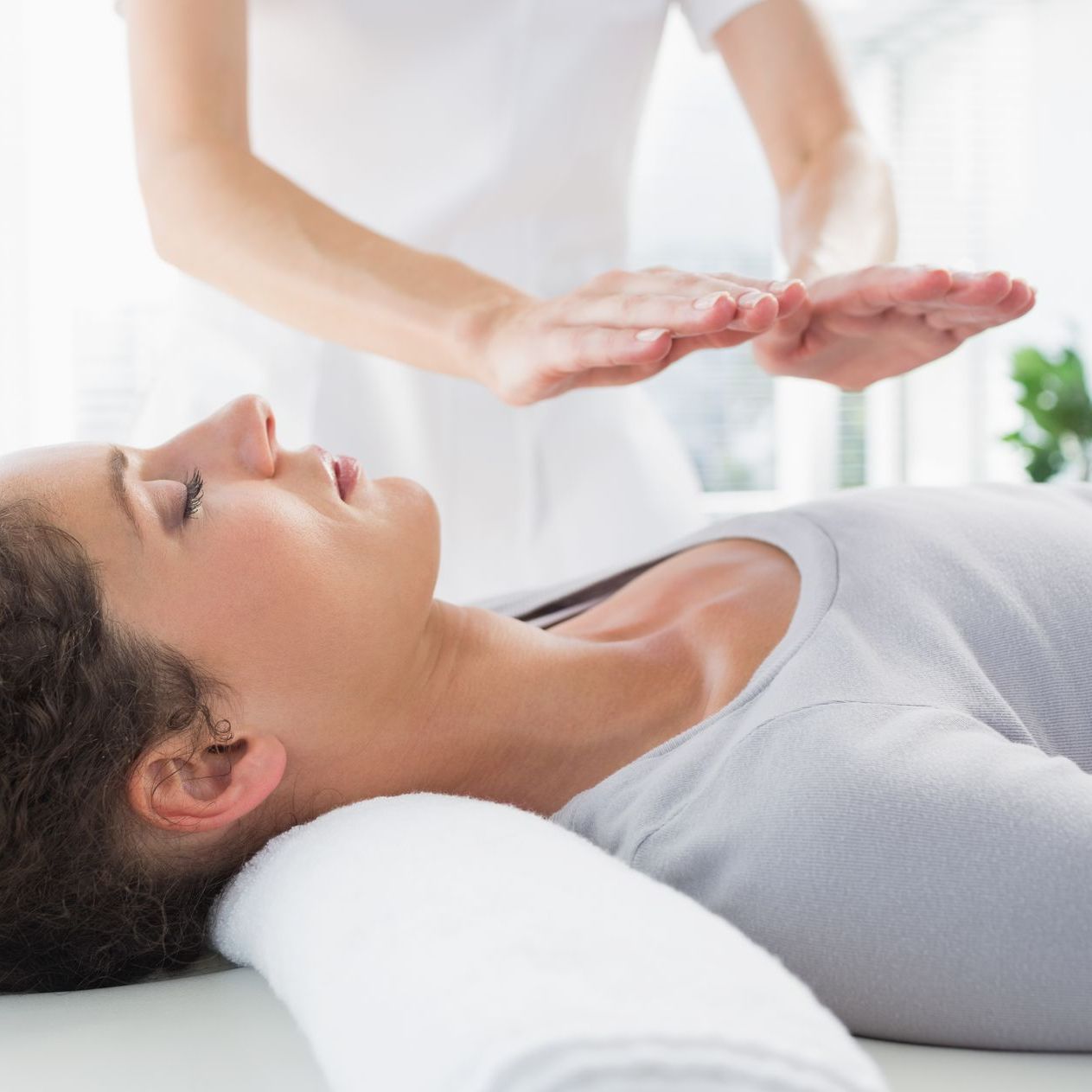 a woman is laying on a bed getting a reiki treatment